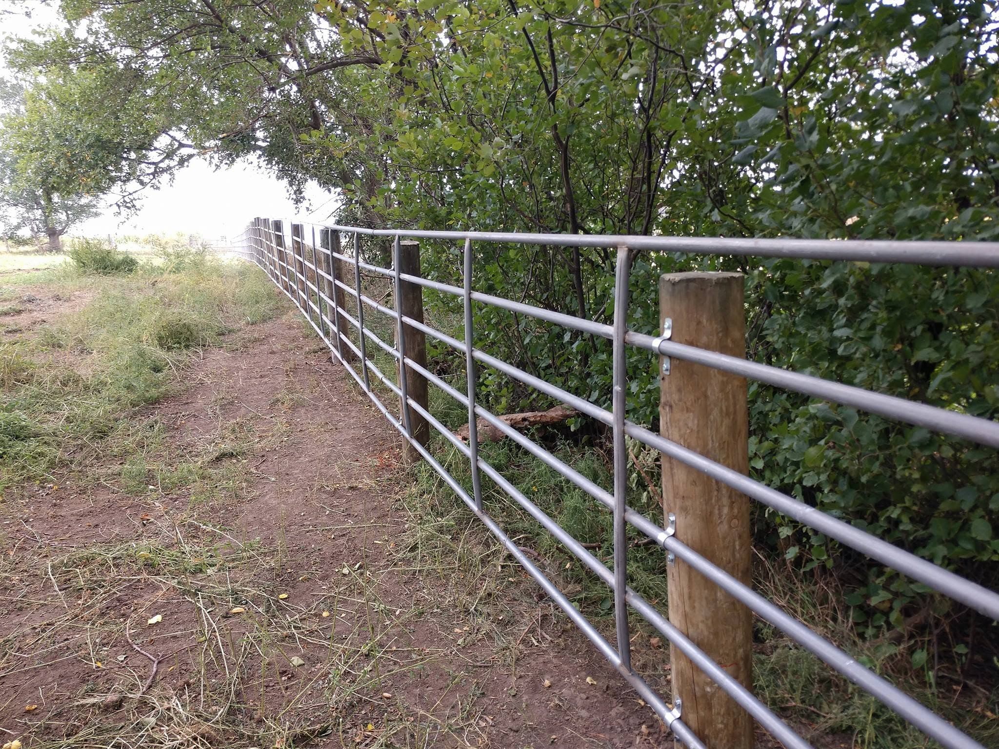 Fence line climbing a red-dirt rise on a fresh build