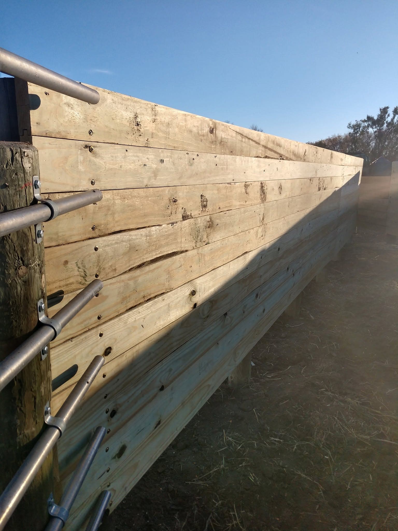 Close view of a board windbreak wall tied into steel pipe framing