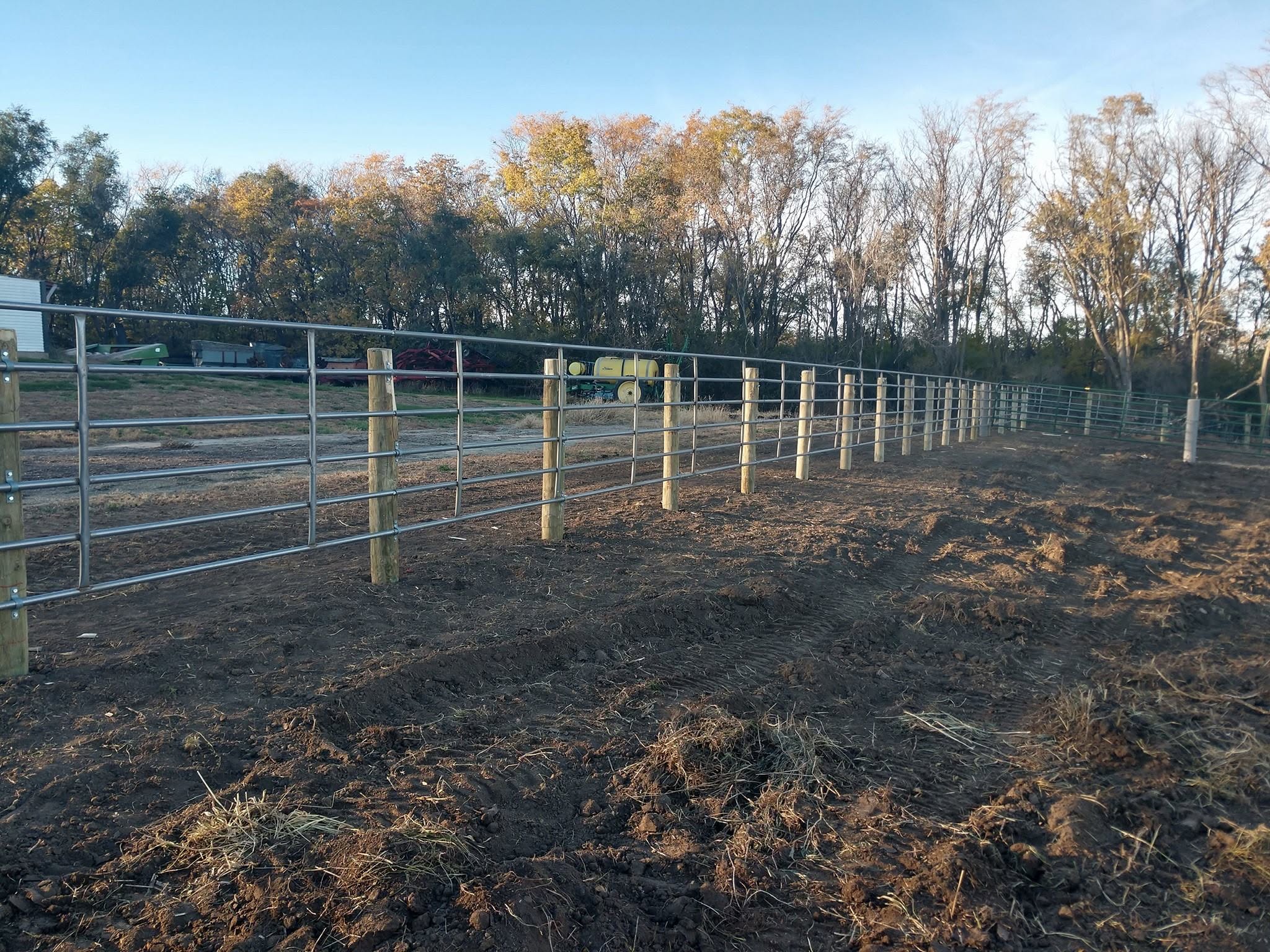 New fence line and gates standing on ground blackened by a range fire