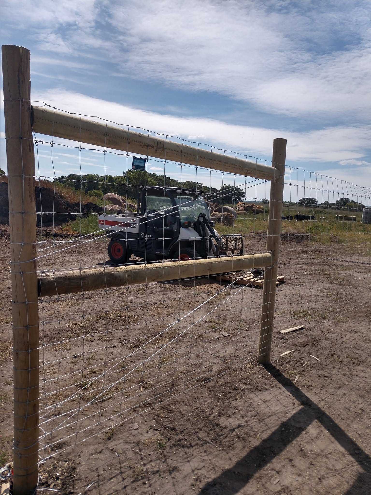 A fresh wood H-brace going up with the skid steer standing by