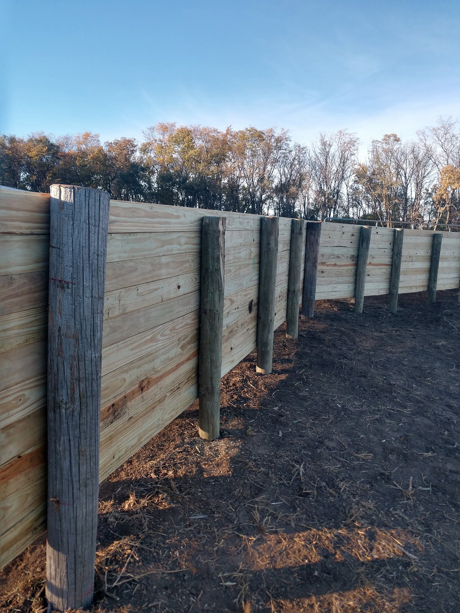 New board windbreak wall on heavy posts against a blue sky
