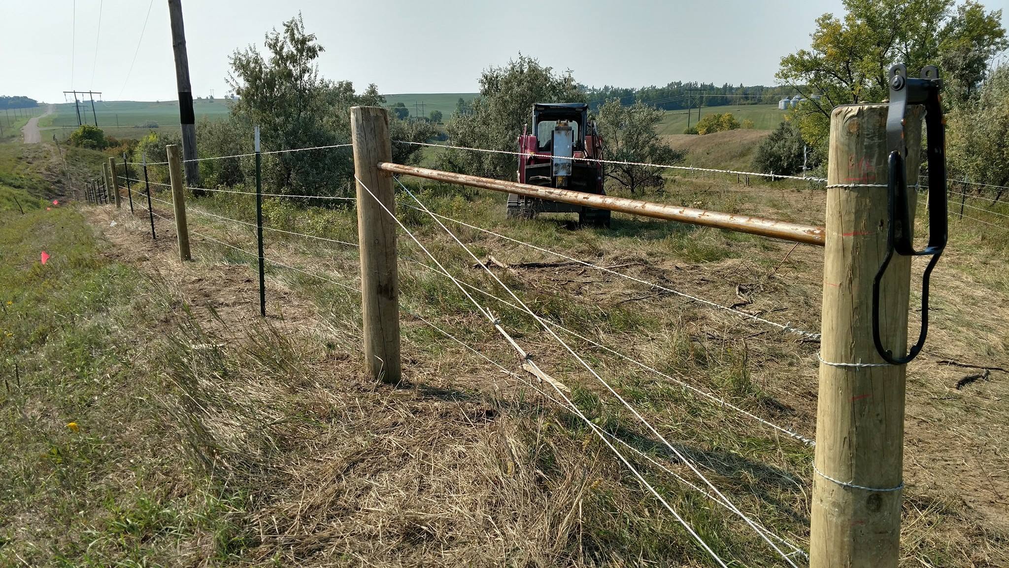 Wire being stretched down a new line with the tractor working behind