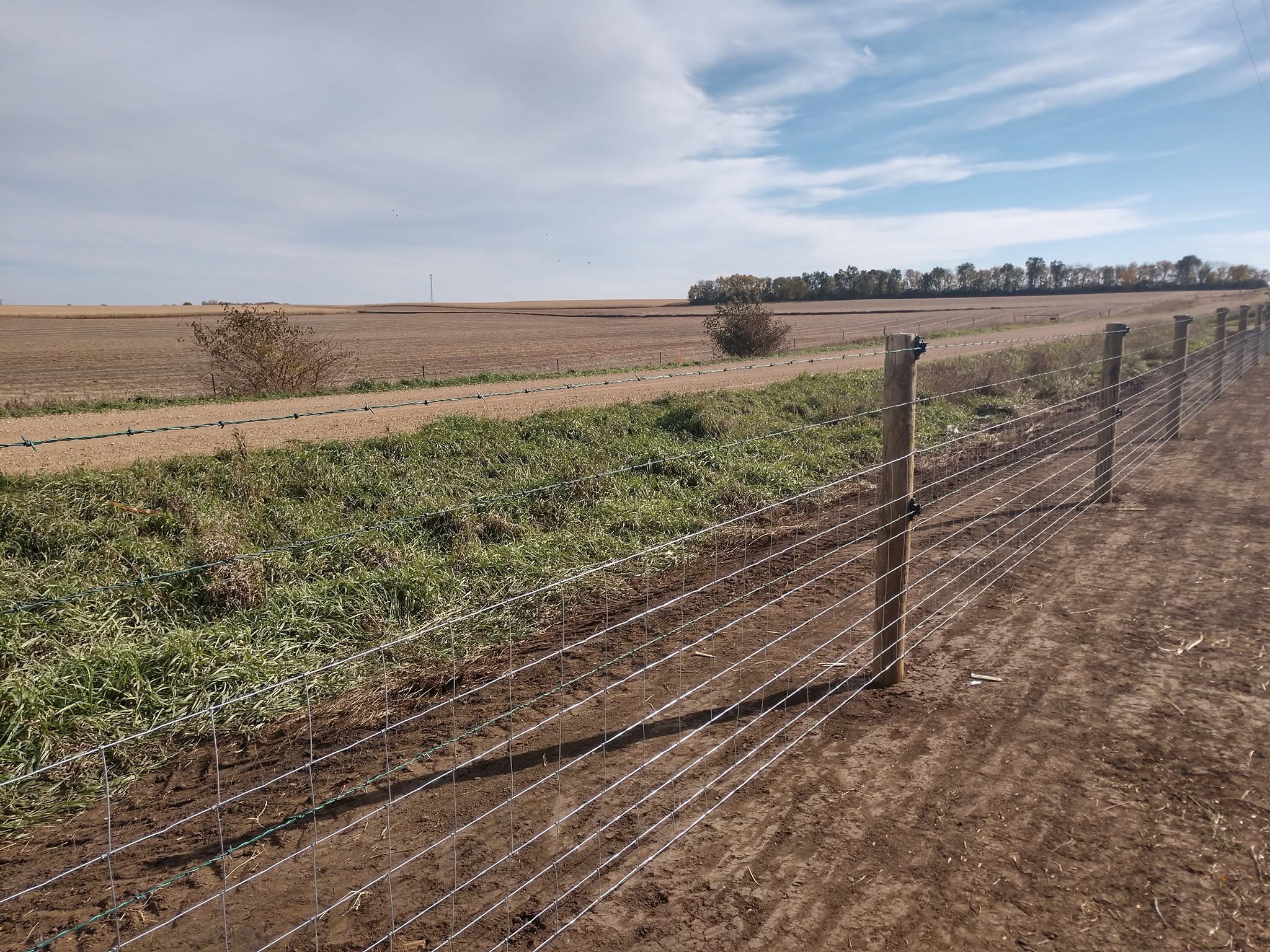 Woven wire fence on wood posts running along a harvested field near Irene SD